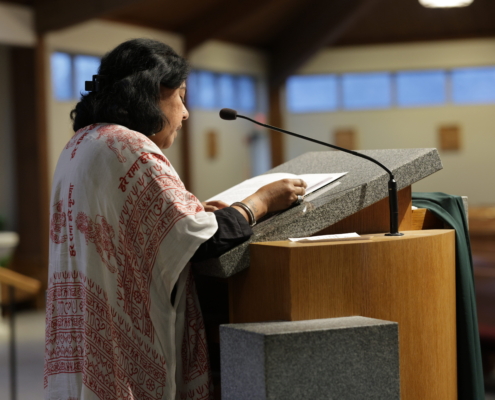 Rumni Saha, interfaith chaplain, speaks at a podium during the Interfaith Thanksgiving Service.