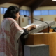 Rumni Saha, interfaith chaplain, speaks at a podium during the Interfaith Thanksgiving Service.